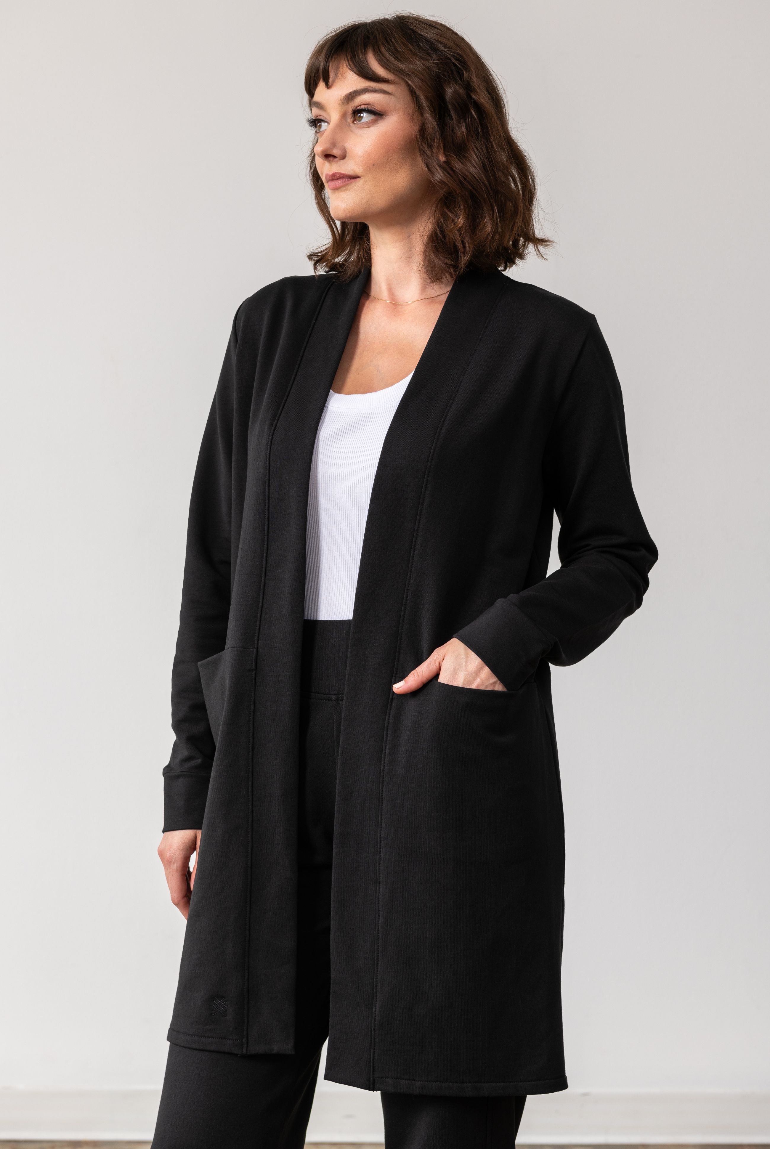 Woman shown wearing black cardigan with her hand in her pocket